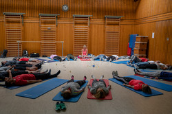 Tag des Schulsports 2022 Teilnehmer*innen liegen beim Workshop "Entspannung in der Grundschule – Traumstunde Weltall" auf Matten im Kreis