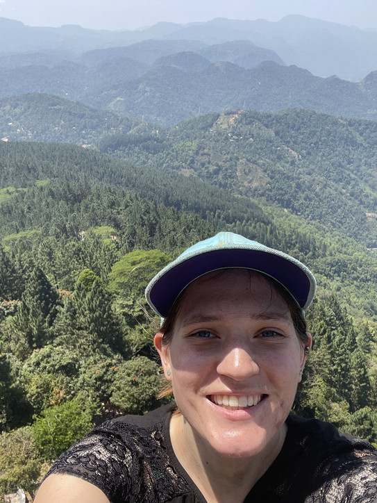 Selfie con Nadja Blasberg mit bewaldeter Berglandschaft im Hintergrund