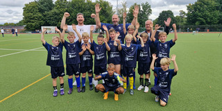 U11 Fußballmannschaft, die jubelnd für ein Mannschaftfoto posiert