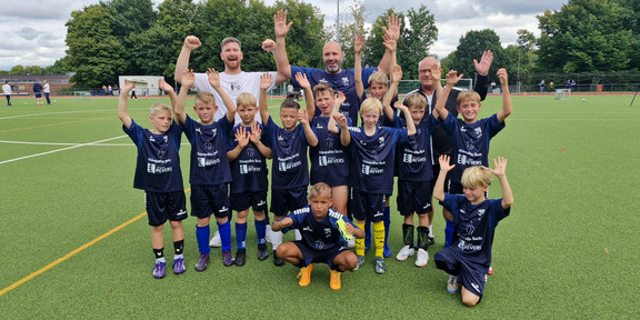 U11 Fußballmannschaft, die jubelnd für ein Mannschaftfoto posiert