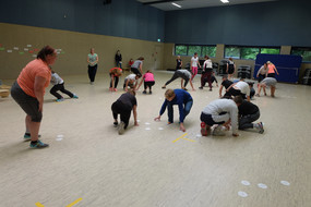 Teilnehmer*innen sammeln in einem Wettkampf Zettel vom Boden auf