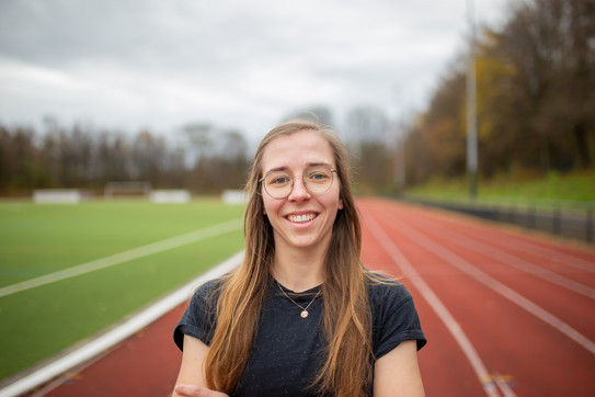 Portraitaufnahme: Hannah Pauly steht auf der Tartanbahn und lacht in die Kamera