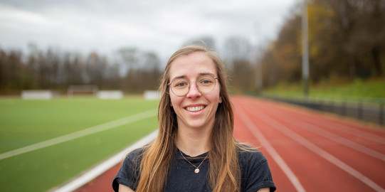 Portraitaufnahme: Hannah Pauly steht auf der Tartanbahn und lacht in die Kamera